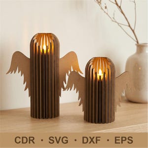 May include: Two brown wooden angel candle holders with cutout wings. The candle holders have a cylindrical shape with vertical slats and a glowing candle inside. The image also includes the text "CDR • SVG • DXF • EPS".
