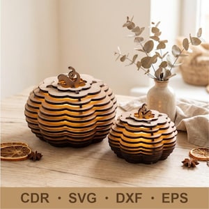 Può includere: Due decorazioni in legno a forma di zucca a strati con una calda luce interna. Ogni pezzo presenta anelli di legno smerlati impilati e un piccolo stelo sulla parte superiore. Il testo CDR, SVG, DXF ed EPS è stampato in fondo all'immagine.