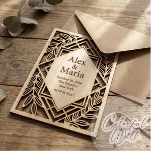 Op de afbeelding: Een houten trouwkaart met lasergesneden geometrische en bladpatronen. De uitnodiging bevat de namen "Alex & Maria" en evenementdetails. Het wordt gepresenteerd met een kraft papieren envelop.