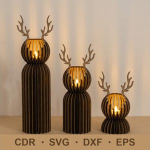 May include: Three wooden reindeer candle holders of varying sizes. Each has a brown, slotted body and a spherical head with antlers. A warm light shines from within each head. The bottom of the image has the text "CDR • SVG • DXF • EPS".