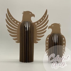 May include: Two brown eagle sculptures. One eagle has outstretched wings with star cutouts. The other eagle is smaller and has a similar design. Both sculptures have a layered, three-dimensional effect. The background is plain white.