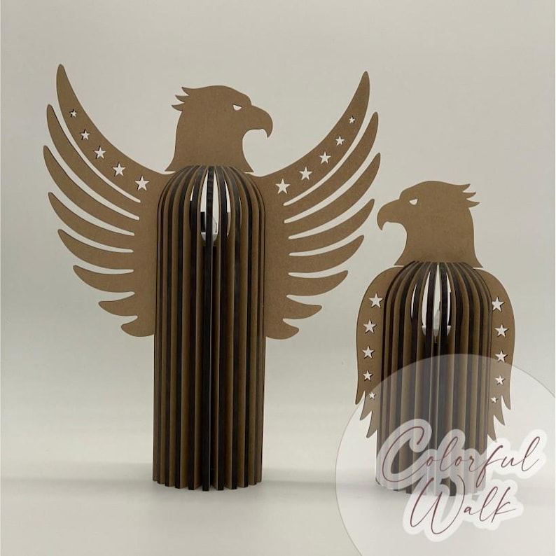 May include: Two brown eagle sculptures. One eagle has outstretched wings with star cutouts. The other eagle is smaller and has a similar design. Both sculptures have a layered, three-dimensional effect. The background is plain white.