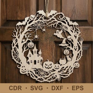 May include: A laser-cut wooden Halloween wreath. The design includes a haunted house, pumpkins, bats, spiders, and a witch's hat. The wreath is made of light-coloured wood and is suspended on a wooden door.