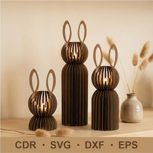 May include: Three brown wooden bunny-shaped candle holders with slotted spherical heads and long ears. The candle holders are of varying heights and are arranged on a wooden surface. The image also includes the text "CDR • SVG • DXF • EPS".