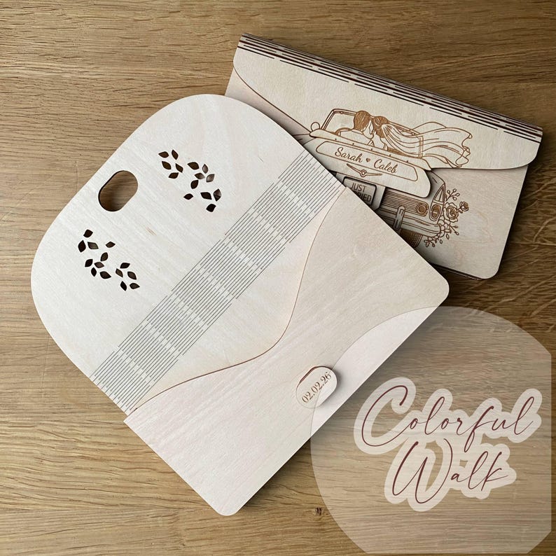 Puede incluir: Dos sobres de invitaci&oacute;n de boda de madera. Uno est&aacute; abierto, con un dise&ntilde;o decorativo de hojas y una serie de l&iacute;neas paralelas. El otro sobre presenta una imagen cortada con l&aacute;ser de una pareja en un coche antiguo con los nombres "Sarah & Caleb".