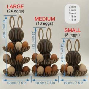 Puede incluir: Tres hueveras de madera marr&oacute;n con forma de conejito, cada una con un n&uacute;mero diferente de huevos. La m&aacute;s grande mide 40 cm de alto y contiene 24 huevos. La mediana mide 32 cm de alto y contiene 16 huevos. La m&aacute;s peque&ntilde;a mide 24 cm de alto y contiene 8 huevos.