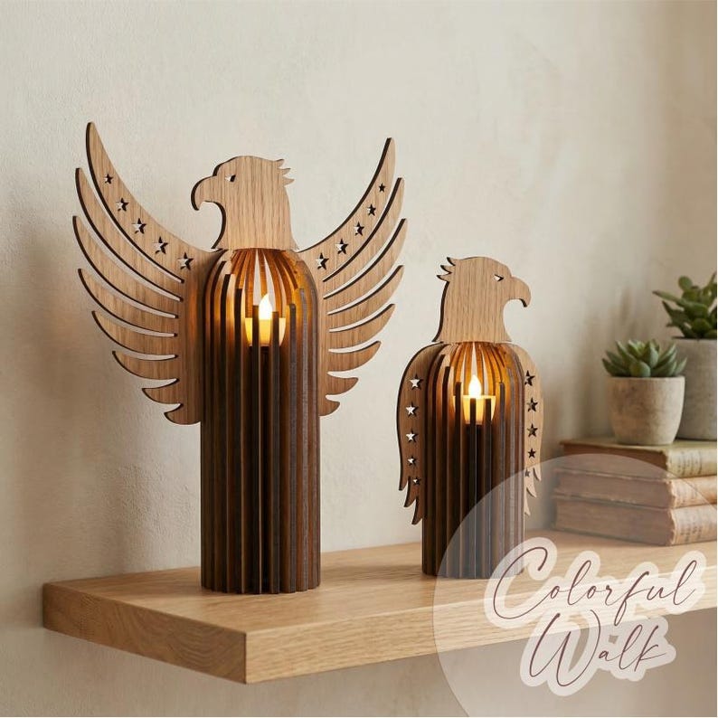 May include: Two wooden eagle candle holders with star cutouts. The eagle heads and wings are light brown, while the bodies are a darker brown. Each holder has a small, glowing candle inside. The candle holders are on a wooden shelf.