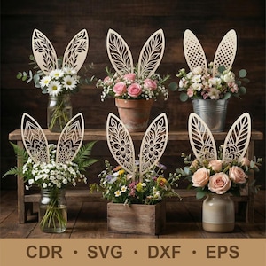 Op de afbeelding: Houten paashaas oordecoraties met ingewikkelde uitgesneden ontwerpen, geplaatst in diverse bloemstukken. De arrangementen bevatten madeliefjes, rozen en andere bloemen in glazen potten, een terracotta pot, een metalen emmer, een houten kist en een keramische vaas. De afbeelding bevat ook de tekst: CDR, SVG, DXF, EPS.