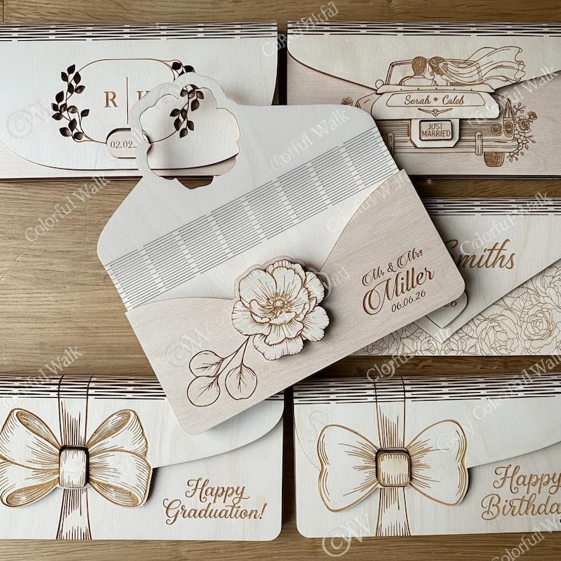 Puede incluir: Cajas de invitaci&oacute;n de madera cortadas con l&aacute;ser con varios dise&ntilde;os. Una presenta un dise&ntilde;o floral, otra un lazo y otras incluyen texto como "&iexcl;Feliz graduaci&oacute;n!" y "Reci&eacute;n casados".