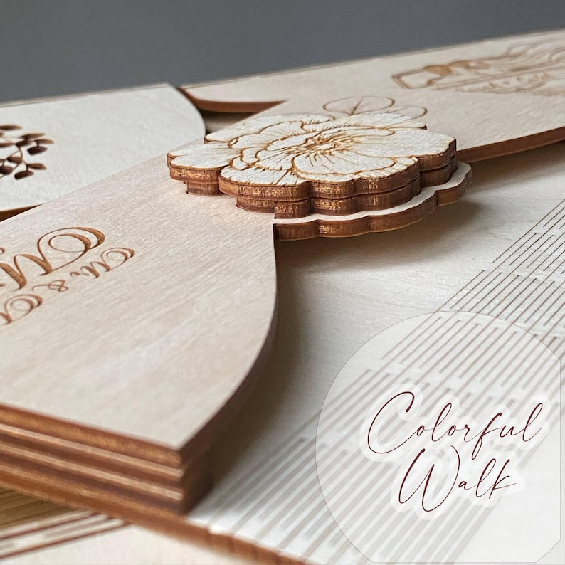 Puede incluir: Primer plano de invitaciones de boda de madera cortadas con l&aacute;ser. Las invitaciones presentan un dise&ntilde;o floral y las palabras "Mr & Mrs" grabadas en la madera. Una flor decorativa est&aacute; unida a la invitaci&oacute;n. El texto "Colorful Walk" tambi&eacute;n es visible.