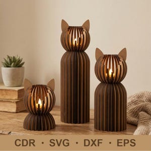 Op de afbeelding: Drie bruine katvormige kandelaars met een gleufontwerp. De kandelaars hebben een cilindrisch lichaam en een kop met puntige oren. De kaarsen binnenin zijn aangestoken en geven een warme gloed. De onderkant van de afbeelding heeft de tekst: CDR • SVG • DXF • EPS.