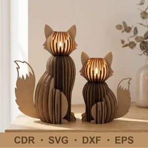 Op de afbeelding: Twee vossenvormige kandelaars gemaakt van gelaagd bruin hout. Elk figuur heeft een lattenontwerp met een hol midden voor een kaars, wat zorgt voor een warme gloed. De tekst CDR, SVG, DXF en EPS staat onderaan de afbeelding gedrukt.