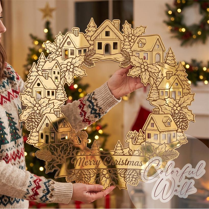 Puede incluir: Una corona navide&ntilde;a circular de tono dorado que presenta una escena de pueblo detallada con casas, pinos, hojas de acebo y pi&ntilde;as. La secci&oacute;n inferior incluye una pancarta con el texto Merry Christmas en una fuente de estilo manuscrito.