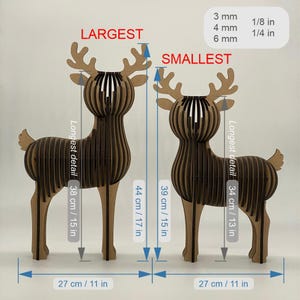 Puede incluir: Dos esculturas de ciervos de madera, una etiquetada como "LARGEST" y la otra como "SMALLEST". El ciervo m&aacute;s grande mide 38 cm de alto y 27 cm de ancho, mientras que el m&aacute;s peque&ntilde;o mide 34 cm de alto y 27 cm de ancho. Ambos tienen un dise&ntilde;o ranurado.