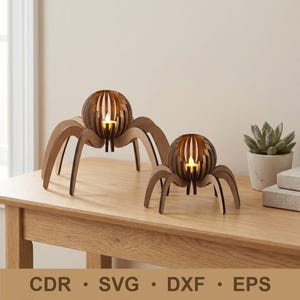 May include: Two wooden spider-shaped candle holders with a spherical center and eight legs. The center has vertical slits, and a lit candle is inside. The holders are on a wooden table. The bottom of the image has the text "CDR • SVG • DXF • EPS".