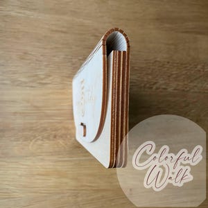 May include: A light-colored wooden box with a curved flap and a small clasp. The text "Happy Birthday" is engraved on the front. The box is made of layered wood and has a natural wood grain.
