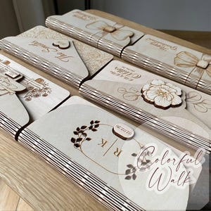 Puede incluir: Una colecci&oacute;n de tarjetas y elementos decorativos de madera cortados con l&aacute;ser. Las tarjetas presentan dise&ntilde;os grabados, incluyendo patrones florales, lazos y texto personalizado. El color es madera natural con un tono marr&oacute;n claro.