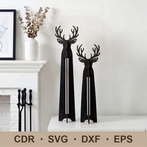 May include: Two black wooden deer sculptures with antlers, standing on a white surface. The deer have a long, vertical design with a white stripe down the center. The image also includes the text "CDR • SVG • DXF • EPS".