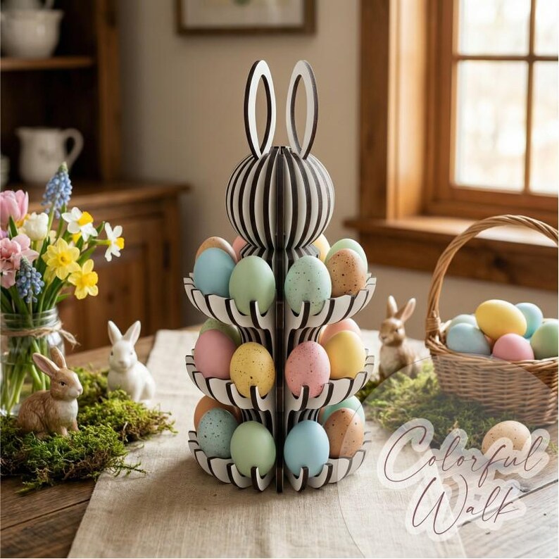 Puede incluir: Un expositor de huevos de Pascua en forma de conejo, con huevos de colores pastel. El conejo es de rayas blancas y negras con orejas blancas. Tambi&eacute;n hay una cesta de huevos y conejos decorativos.