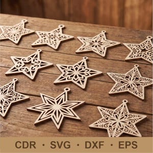 Puede incluir: Una colección de diez adornos de estrella de madera de color marrón claro, cada uno con patrones geométricos y florales cortados con láser. Las estrellas están dispuestas en una cuadrícula y el texto CDR, SVG, DXF, EPS aparece en la parte inferior.