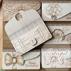 May include: Wooden laser-cut gift boxes with various designs, including a treasure chest, floral patterns, balloons, and bows. The boxes are light brown with engraved details and text that reads "Happy Graduation!" and "Colorful Walk Happy Birthday!"