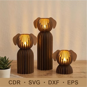 以下が含まれることがあります： LEDライト付きの、茶色の木製犬型キャンドルホルダー3つ。 キャンドルホルダーはスロットデザインで、サイズはさまざまです。 画像には「CDR • SVG • DXF • EPS」の文字も含まれています。