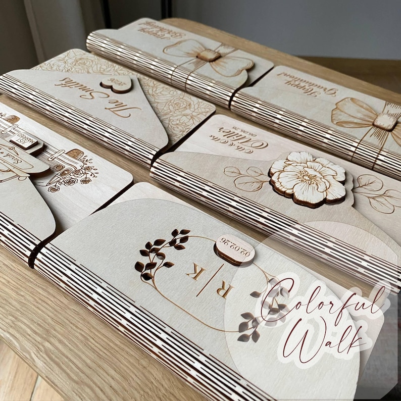 May include: A collection of laser-cut wooden cards and decorative items. The cards feature engraved designs, including floral patterns, bows, and personalized text. The color is natural wood with a light brown hue.