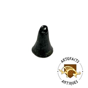 May include: A dark, bell-shaped antique artifact with a hole at the top. The object has a weathered appearance, with hints of green oxidation. The image includes a logo for "ARTEFACTS ANTIQUES."