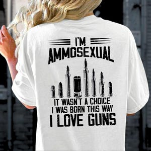 Puede incluir: Camiseta blanca con el texto "I'M AMMOSEXUAL" sobre un gr&aacute;fico de balas. Debajo del gr&aacute;fico, el texto dice "IT WASN'T A CHOICE I WAS BORN THIS WAY I LOVE GUNS".