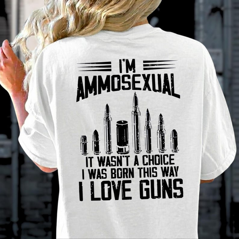 Puede incluir: Camiseta blanca con el texto "I'M AMMOSEXUAL" sobre un gr&aacute;fico de balas. Debajo del gr&aacute;fico, el texto dice "IT WASN'T A CHOICE I WAS BORN THIS WAY I LOVE GUNS".