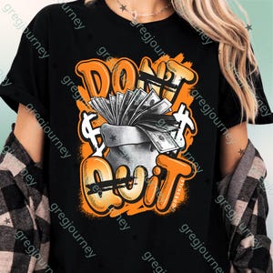 May include: Black t-shirt with an orange and white graphic. The graphic features the words "DON'T QUIT" in an orange graffiti-style font, with a money bag overflowing with cash in the center.