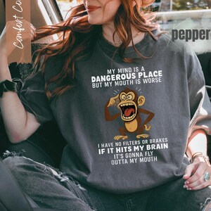 May include: Dark gray t-shirt with the text "MY MIND IS A DANGEROUS PLACE BUT MY MOUTH IS WORSE" and a cartoon monkey graphic. The shirt also says "I HAVE NO FILTERS OR BRAKES IF IT HITS MY BRAIN IT'S GONNA FLY OUTTA MY MOUTH."