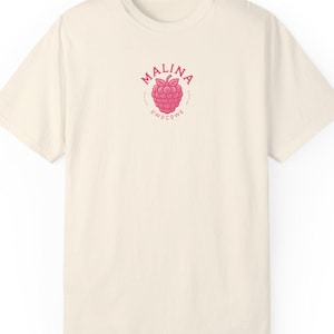 May include: A cream colored t-shirt with a pink raspberry graphic and the text "MALINA PWOCOWE" in a circle.