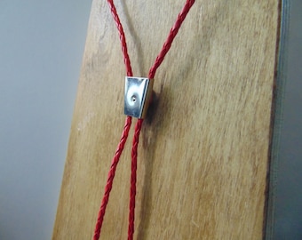May include: A red braided leather bolo tie with a silver metal tip.