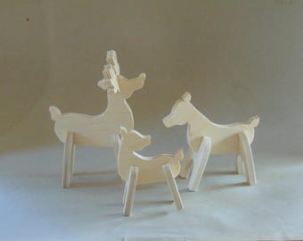 May include: Three wooden reindeer figurines, one large and two smaller, standing on a light beige surface. The reindeer are all made of unfinished wood and have simple, stylized features.
