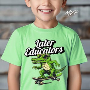 May include: A light green t-shirt with a cartoon alligator wearing sunglasses and skateboarding. The text "Later Educators" is printed in black above the alligator.