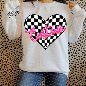 May include: White sweatshirt featuring a black and white chequered heart design with the word "custom" in pink lettering.
