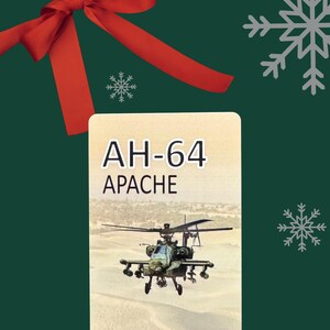 May include: A gift card featuring an AH-64 Apache helicopter over a desert landscape. The card has the text "AH-64 APACHE" in white. The background is dark green with snowflakes and a red bow.