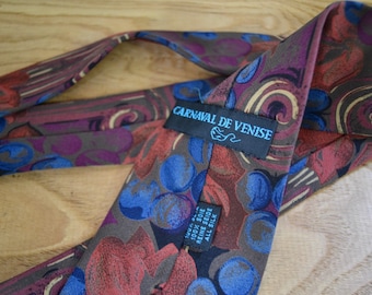 Puede incluir: Una corbata de seda con estampado marrón, rojo y azul con una etiqueta que dice "CARNAVAL DE VENISE" y "100% SOIE REINE SILK ALL SILK".