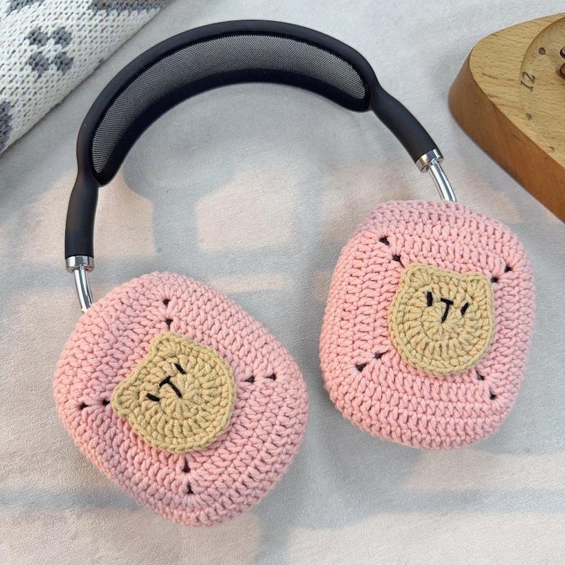 May include: Pink crocheted headphone covers with a brown crocheted bear face on each side.