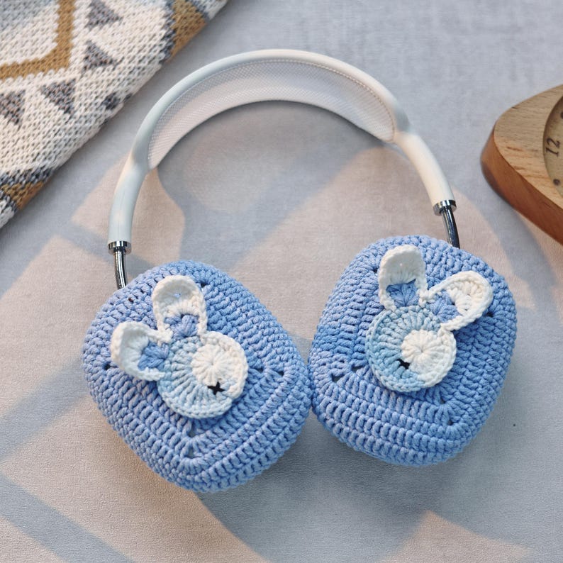 May include: Blue crocheted earmuffs with white bunny ears. The earmuffs are attached to a white headband.