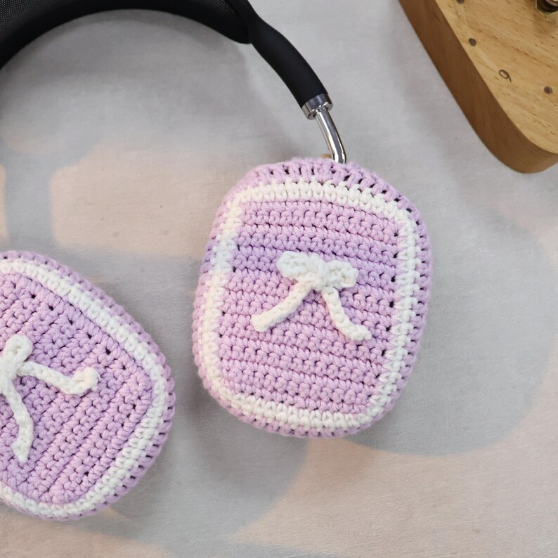 May include: Purple and white crocheted headphone covers with a white bow on each cover.