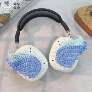 May include: White crocheted headphone covers with blue and green crocheted wings.