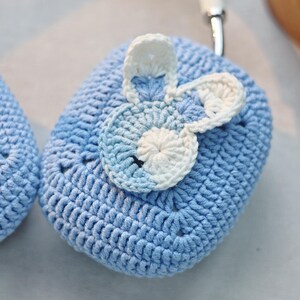 May include: A light blue crocheted case with a white and blue crocheted flower design.