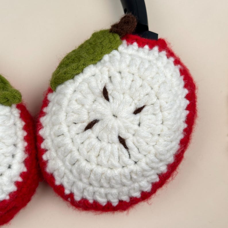 Puede incluir: Fundas de auriculares con forma de manzana tejidas a ganchillo. Las fundas son rojas con centros blancos, semillas marrones y hojas verdes. El dise&ntilde;o de la manzana es un accesorio divertido y &uacute;nico para los auriculares.