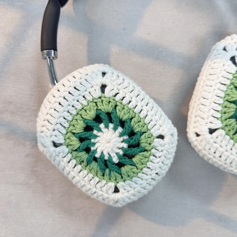 May include: White crocheted headphone covers with a green and white circular pattern in the center.