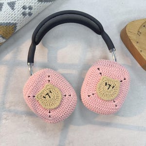 May include: Pink crocheted headphone covers with a brown crocheted bear face on each cover.
