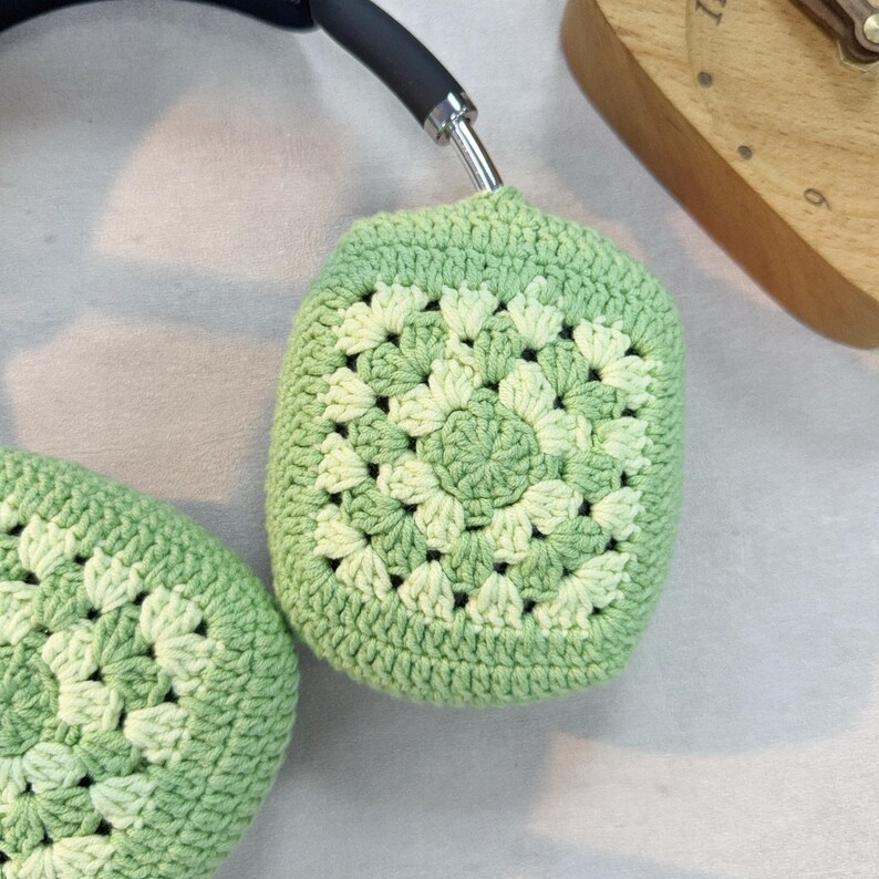 Op de afbeelding: Groene gehaakte oorkappen met een wit en groen granny square patroon.