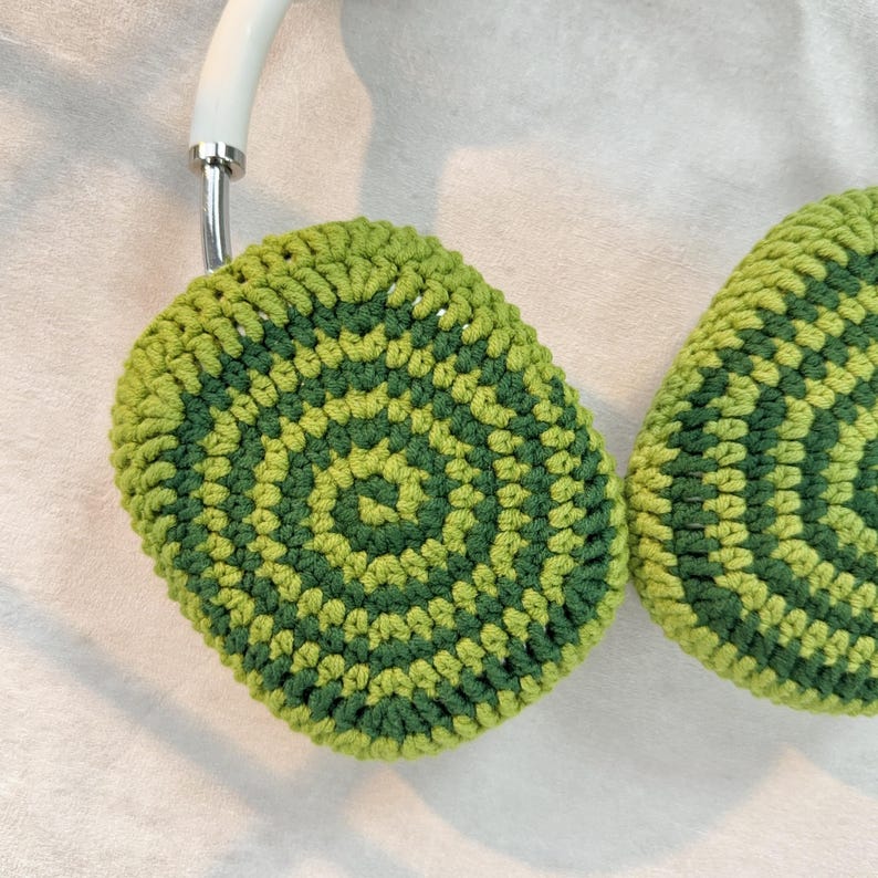Puede incluir: Orejeras de ganchillo verde y verde lima con un patr&oacute;n circular.