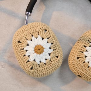 Puede incluir: Un par de fundas para auriculares de ganchillo beige con un dise&ntilde;o de margarita blanca. Las fundas est&aacute;n hechas con un punto de granny square.